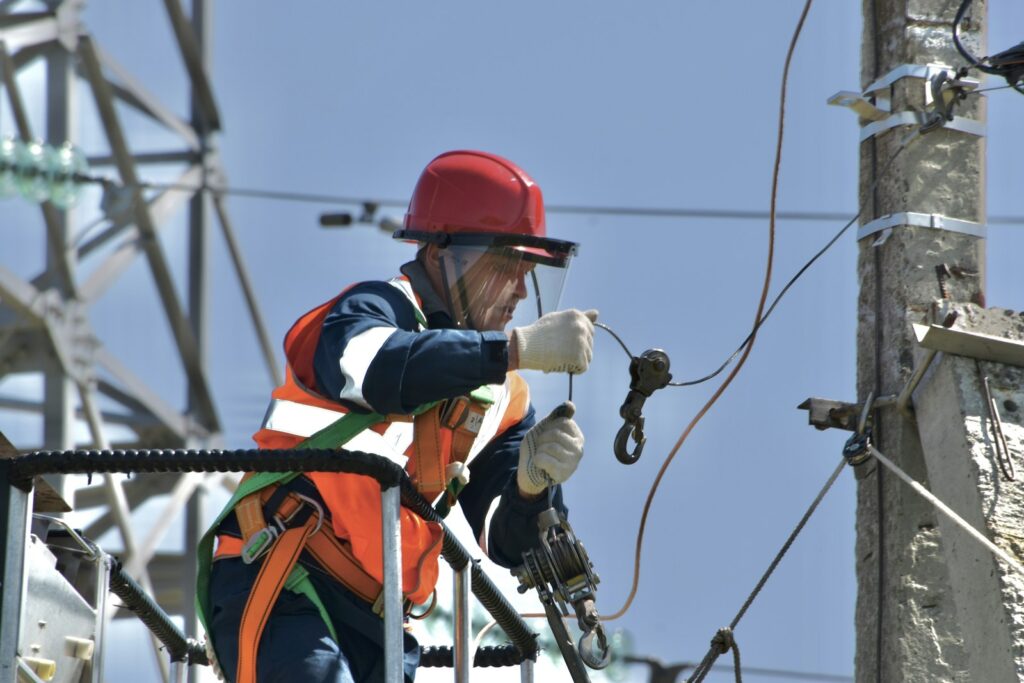 Electrician in safety gear performing electrical line work
