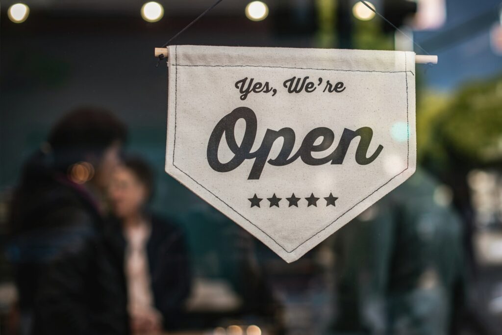 A "Yes, We're Open" sign hanging in a small business storefront window, representing a newly listed business now visible to customers