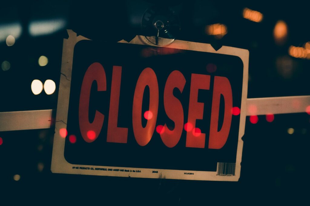 A red and black closed sign hanging in a storefront window, representing a suspended Google Business Profile