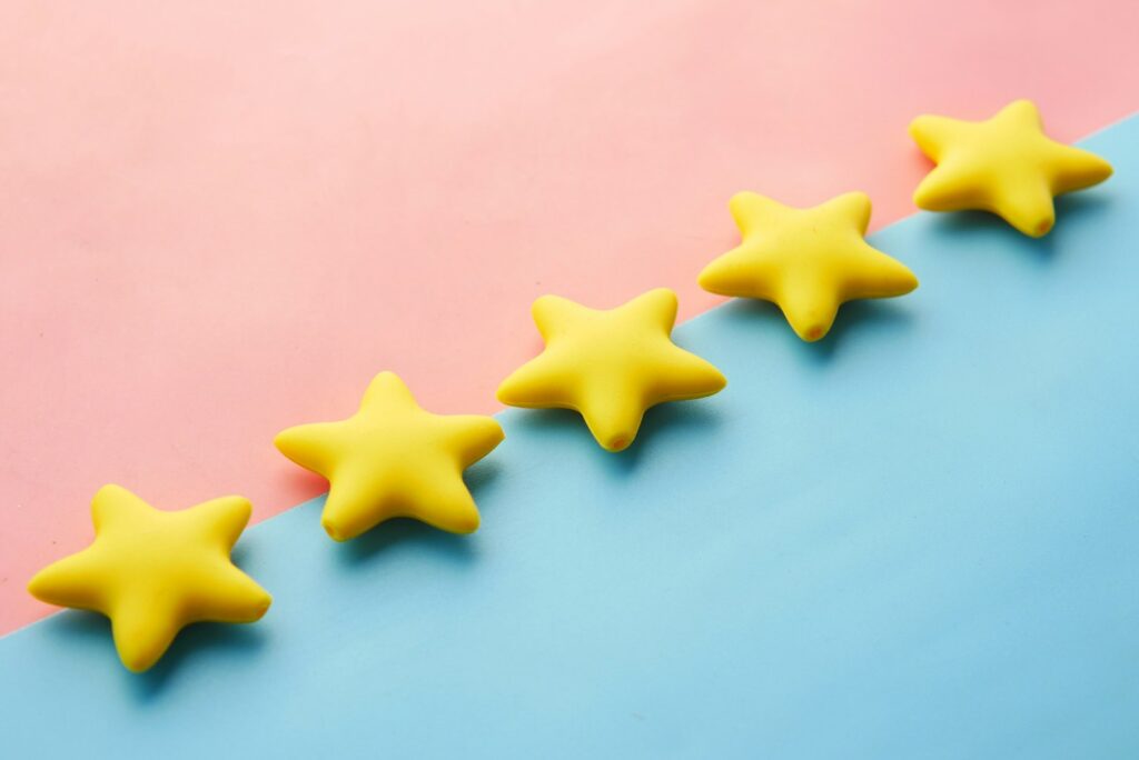 Five gold star icons on a soft blue and pink background, representing a five-star Google review