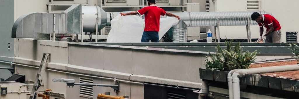 Two HVAC technicians repairing ductwork