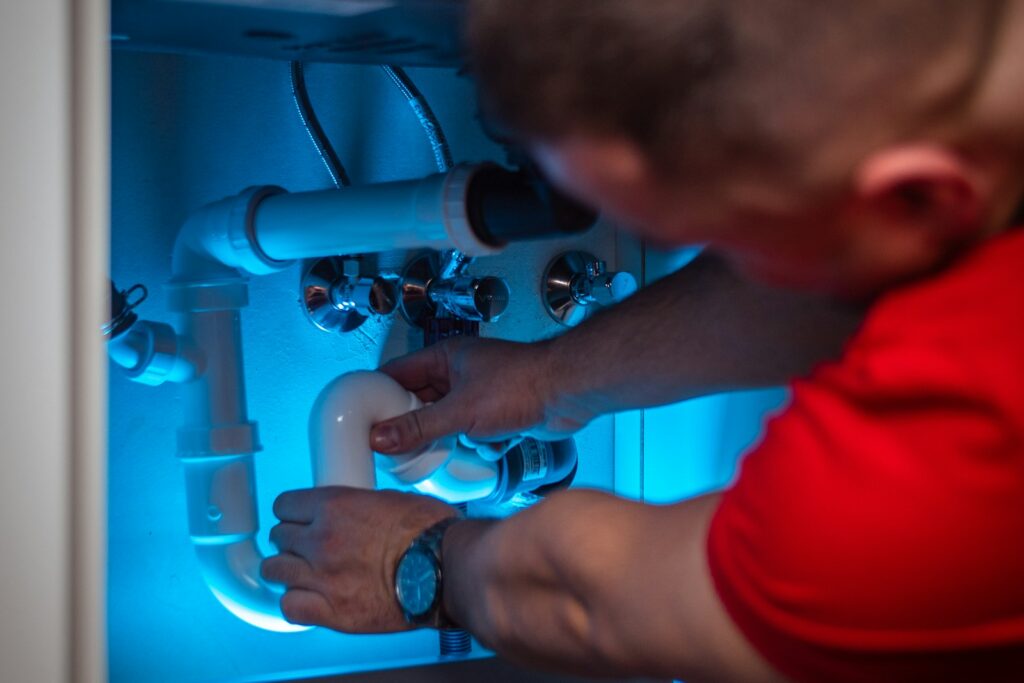 Plumber working on pipes under a cabinet - Google reviews for plumbers