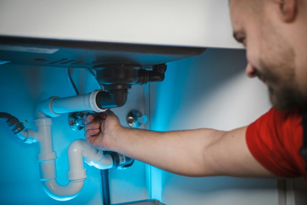 Plumber repairing a pipe under a sink