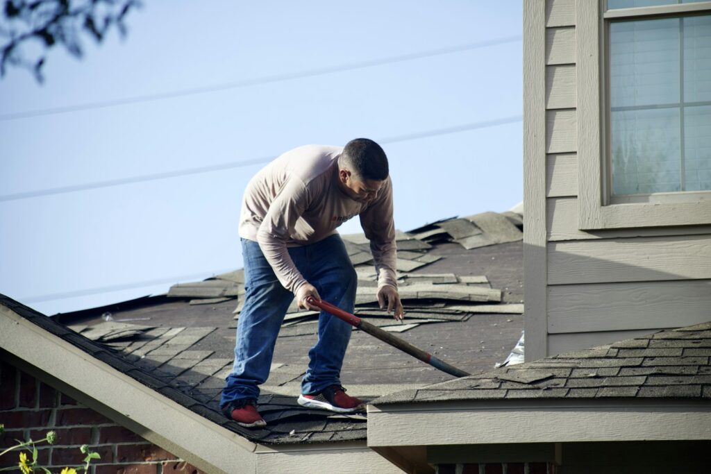 Roofing contractor removing old shingles from a residential roof