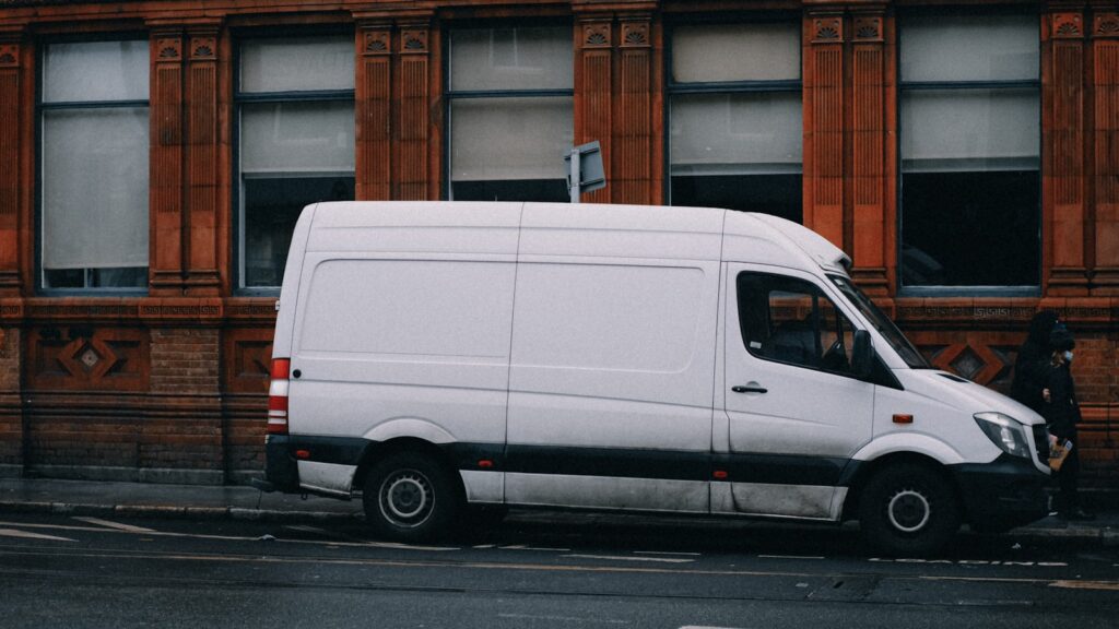 Unmarked white service van parked on a city street, representing a mobile service-area business that travels to customers